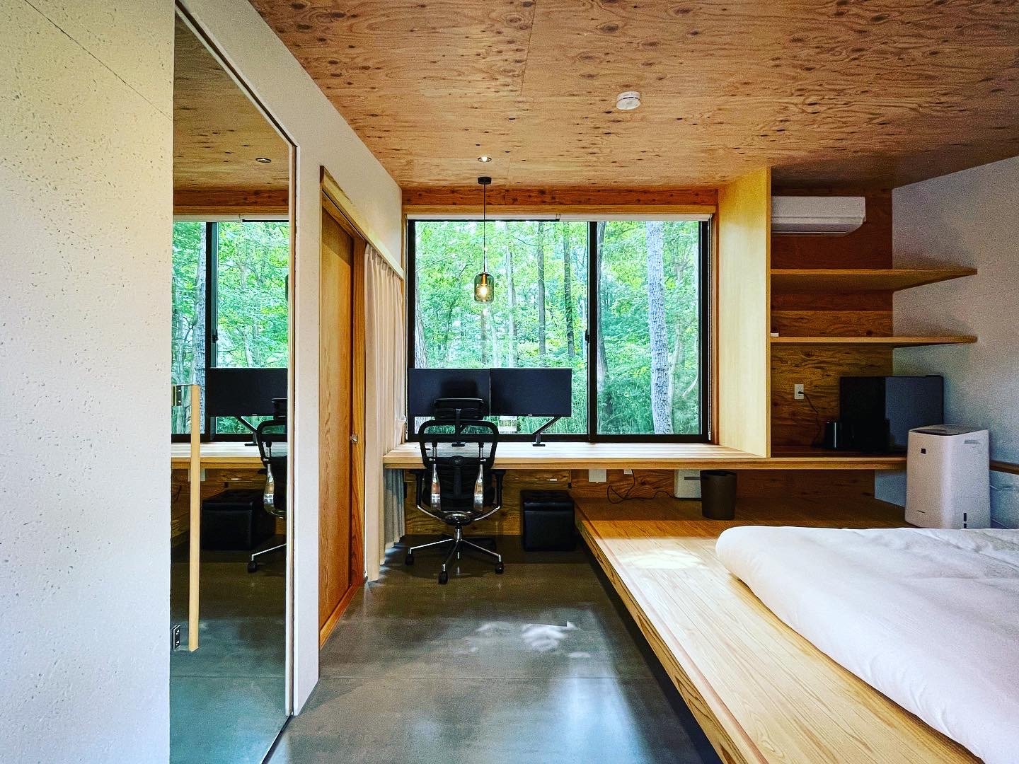 A guest room, with a desk running along a full-width window onto the forest