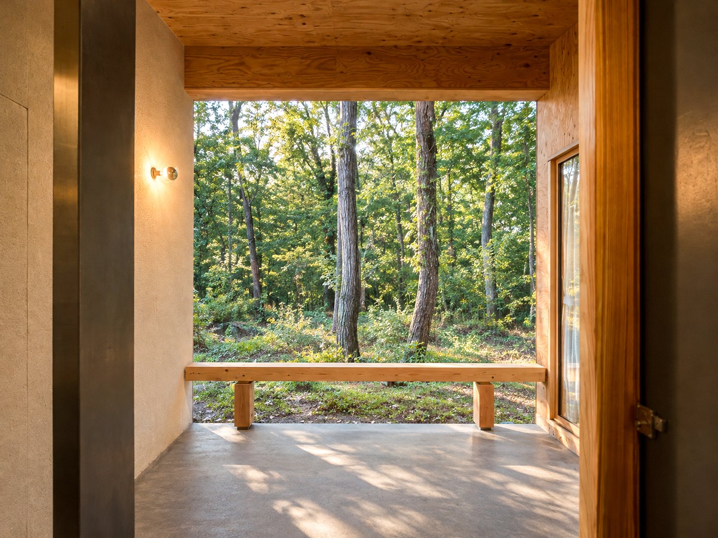 A sheltered bench under the eaves, looking onto the forest